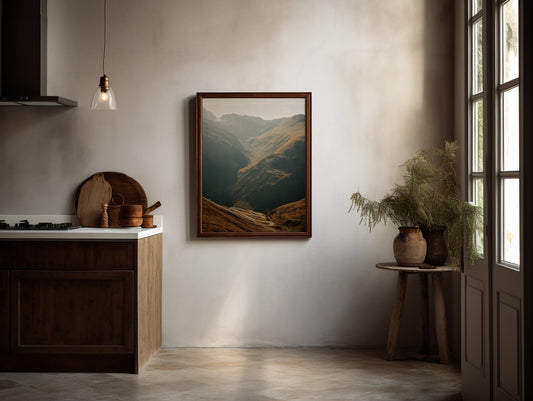 Analog mountain valley landscape print with winding alpine road, shot on 35mm film in the Swiss Alps, displayed in a wooden frame in a warm rustic minimalist kitchen interior