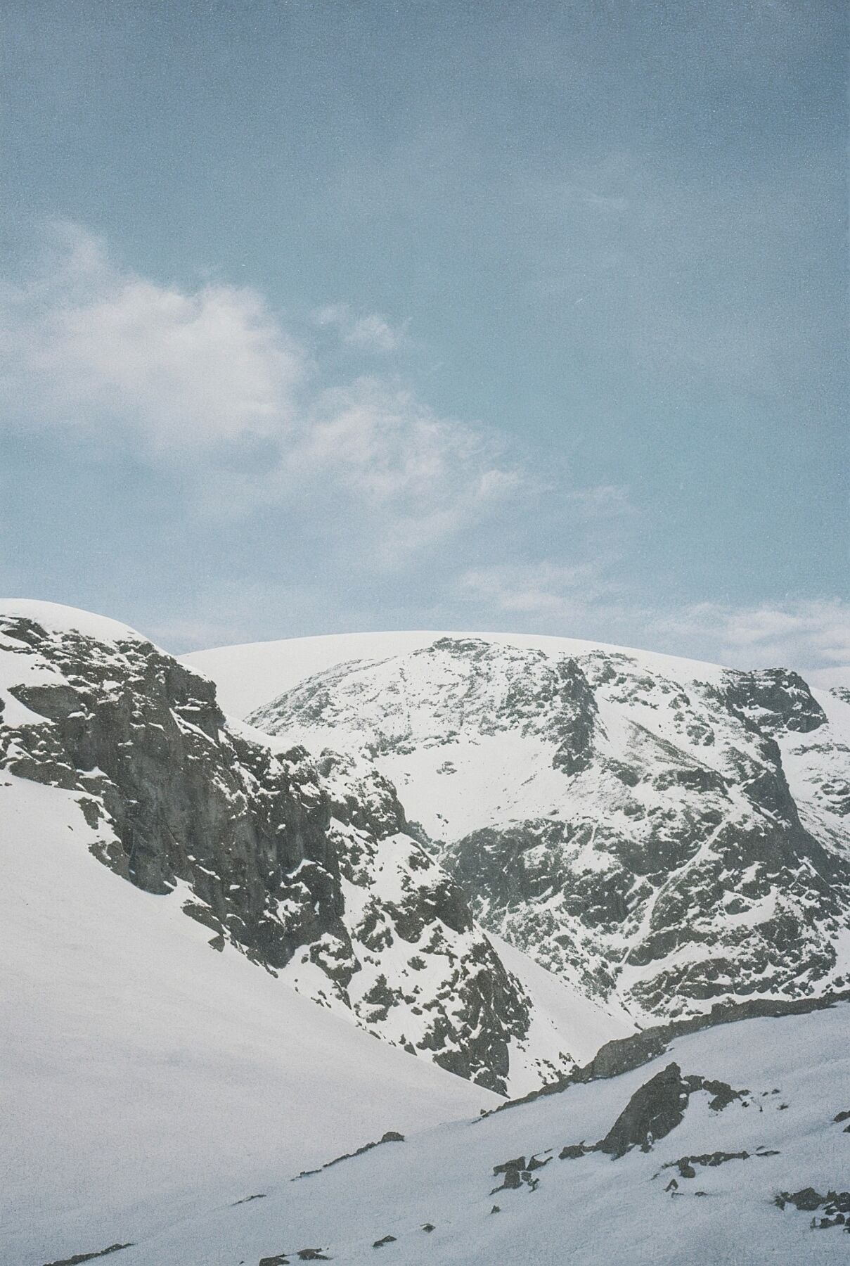 Analog snow covered mountain landscape print with alpine peaks under blue sky, shot on 35mm film in the Swiss Alps with soft natural light