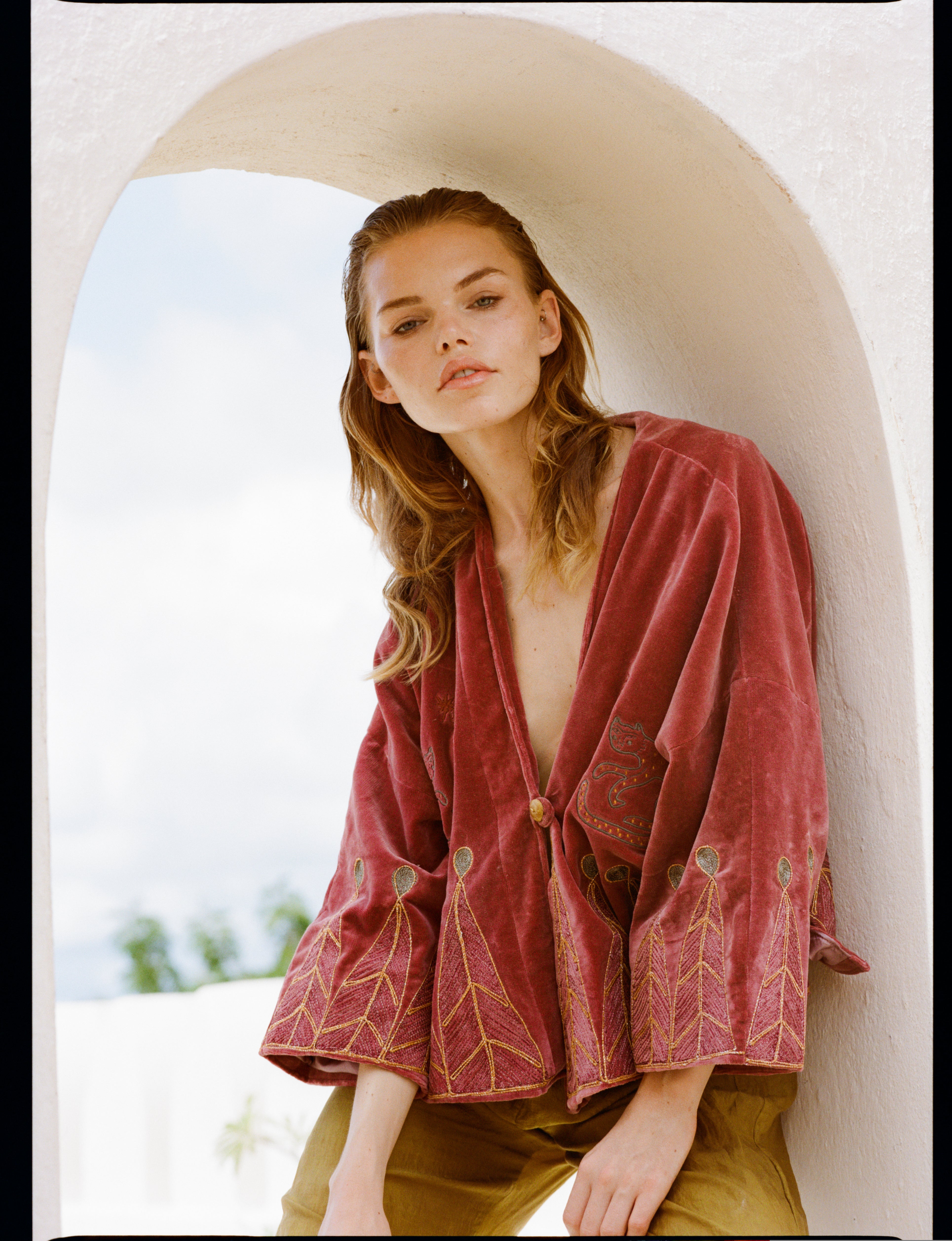 Analog fashion portrait of model wearing HAMAJI in Lamu, Kenya, framed by white arch and soft coastal light, shot on medium format film