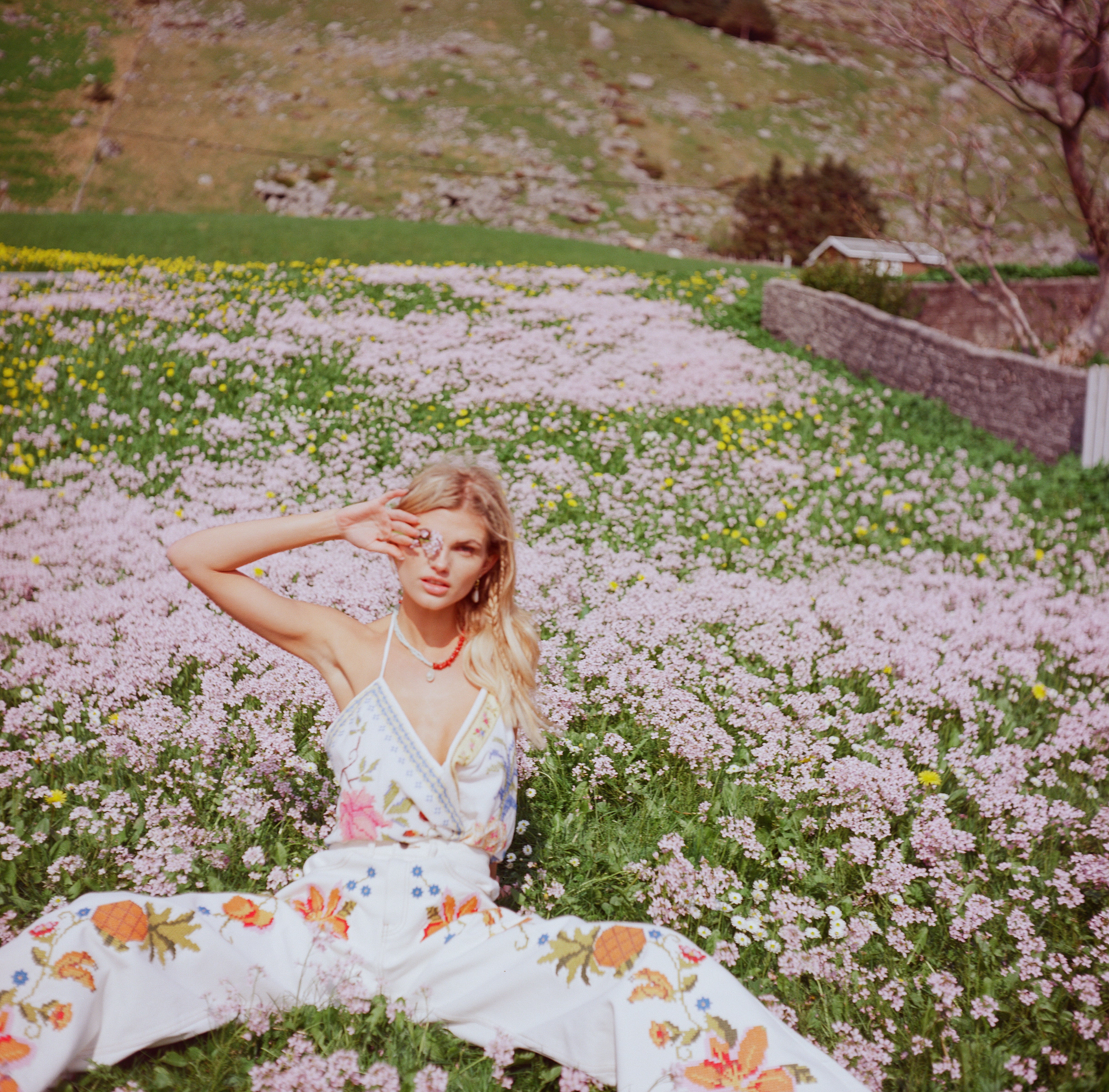 Analog portrait of model lying in a wildflower field in Norway, wearing a patterned dress FARM RIO shot on Rolleicord medium format film