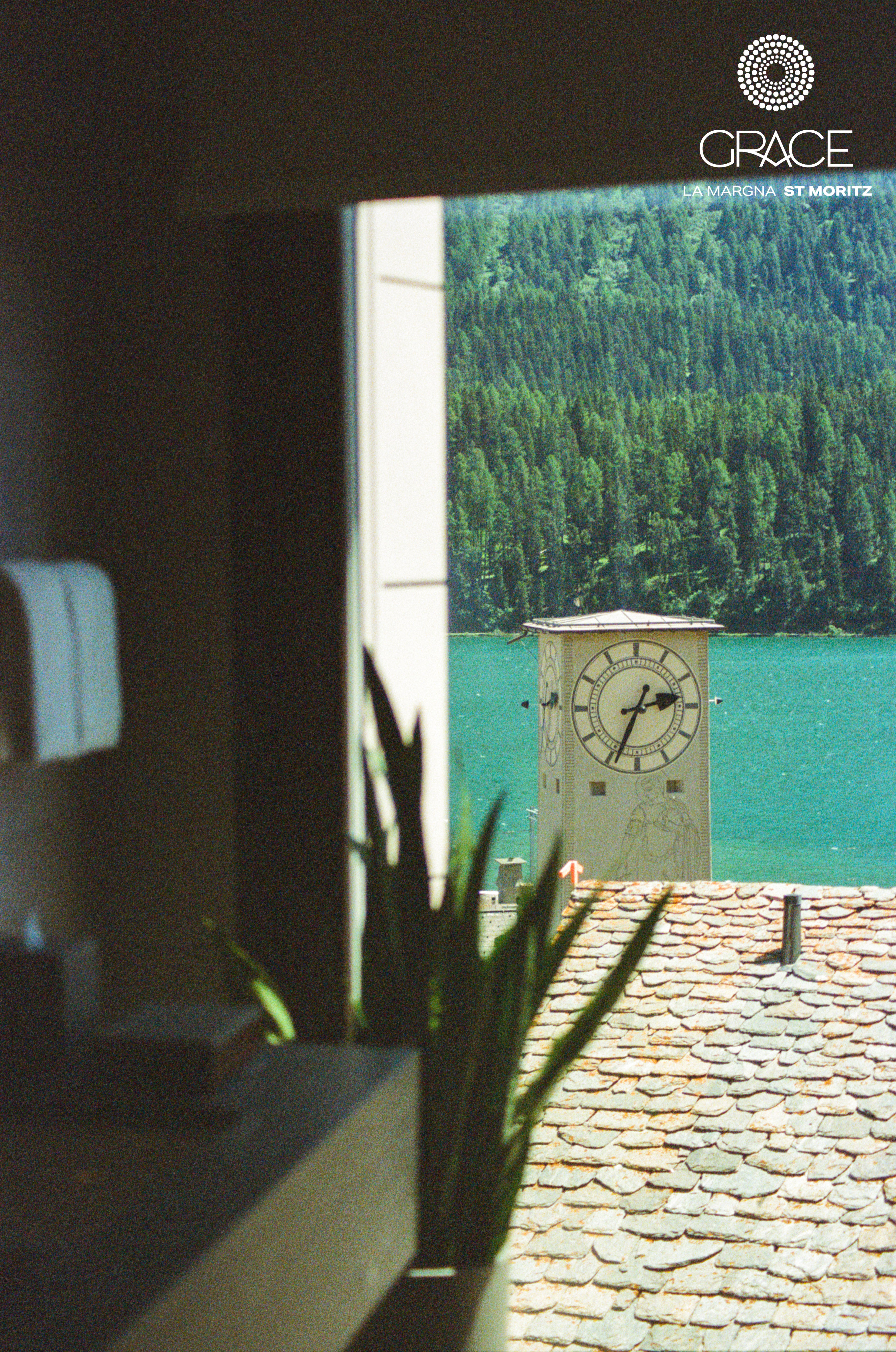 Analog view from interior of Grace La Margna Hotel overlooking clock tower and lake in St Moritz, framed by window and soft foreground, shot on medium format film