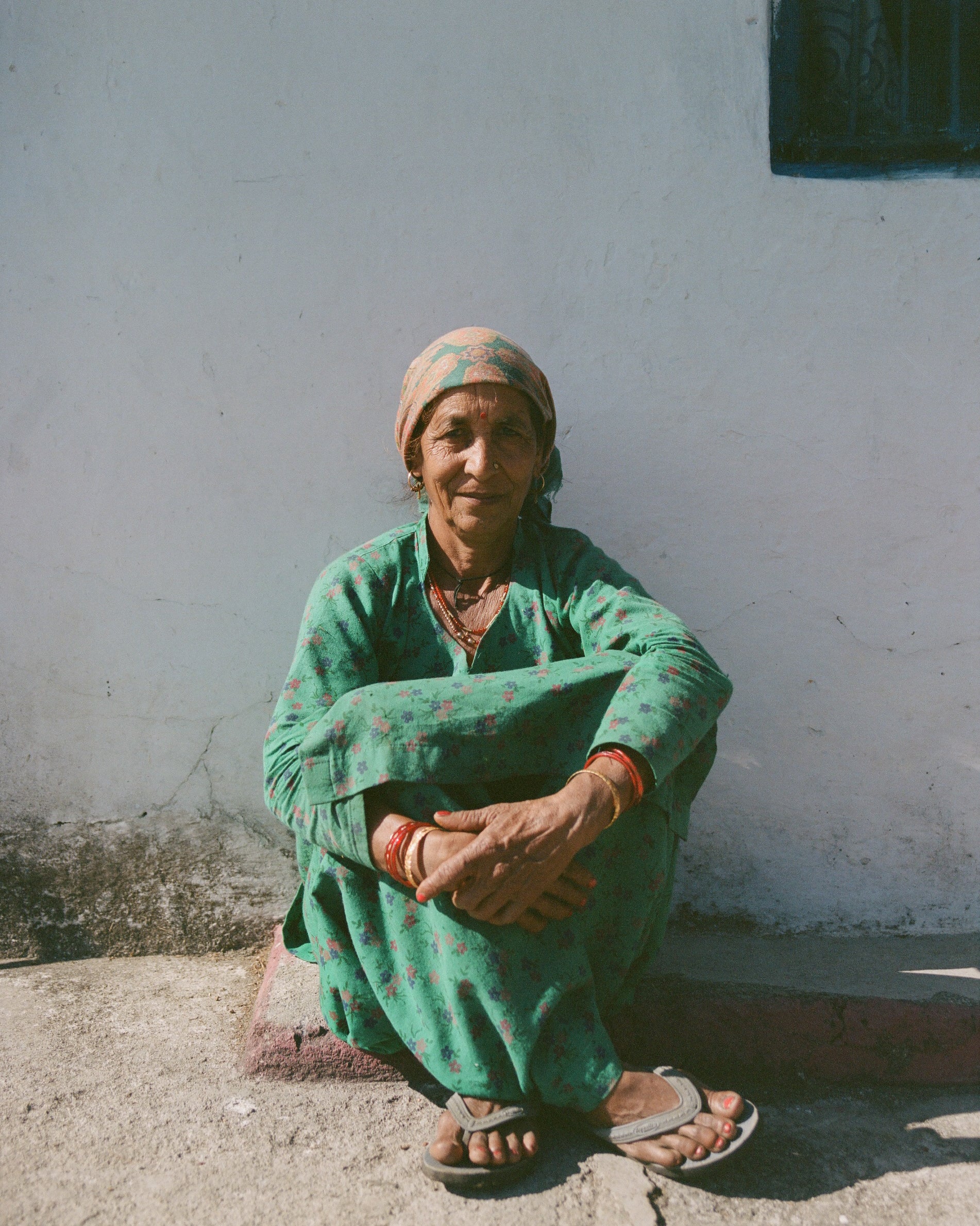 Analog portrait of local woman seated outside in the Indian mountains, wearing traditional clothing, photographed in natural sunlight on medium format film