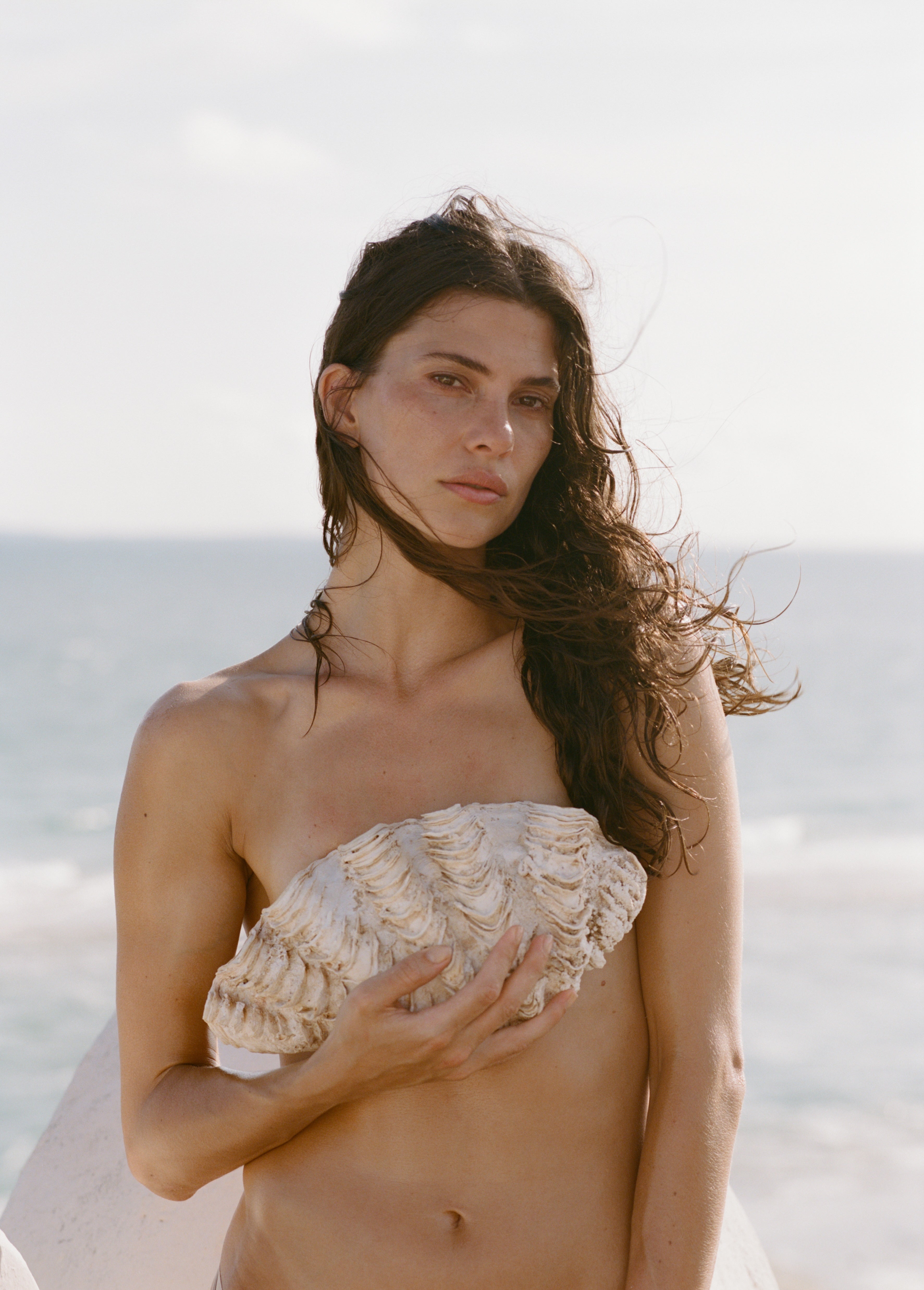 Analog fashion portrait of Courtney Allen holding seashell by the ocean, shot on medium format 120 film in soft natural light
