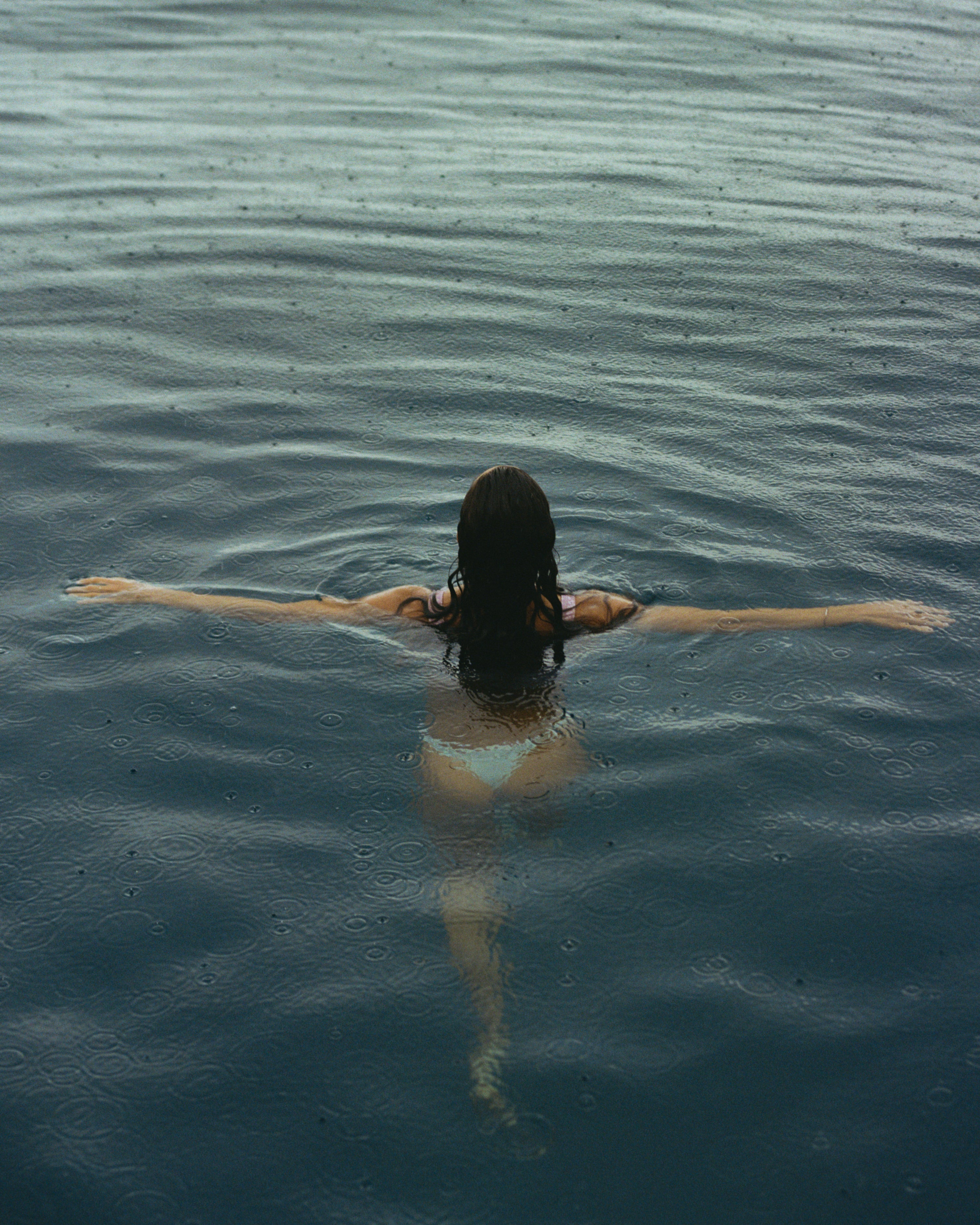 Person floating on their back in a body of water with arms outstretched shot on 120mm