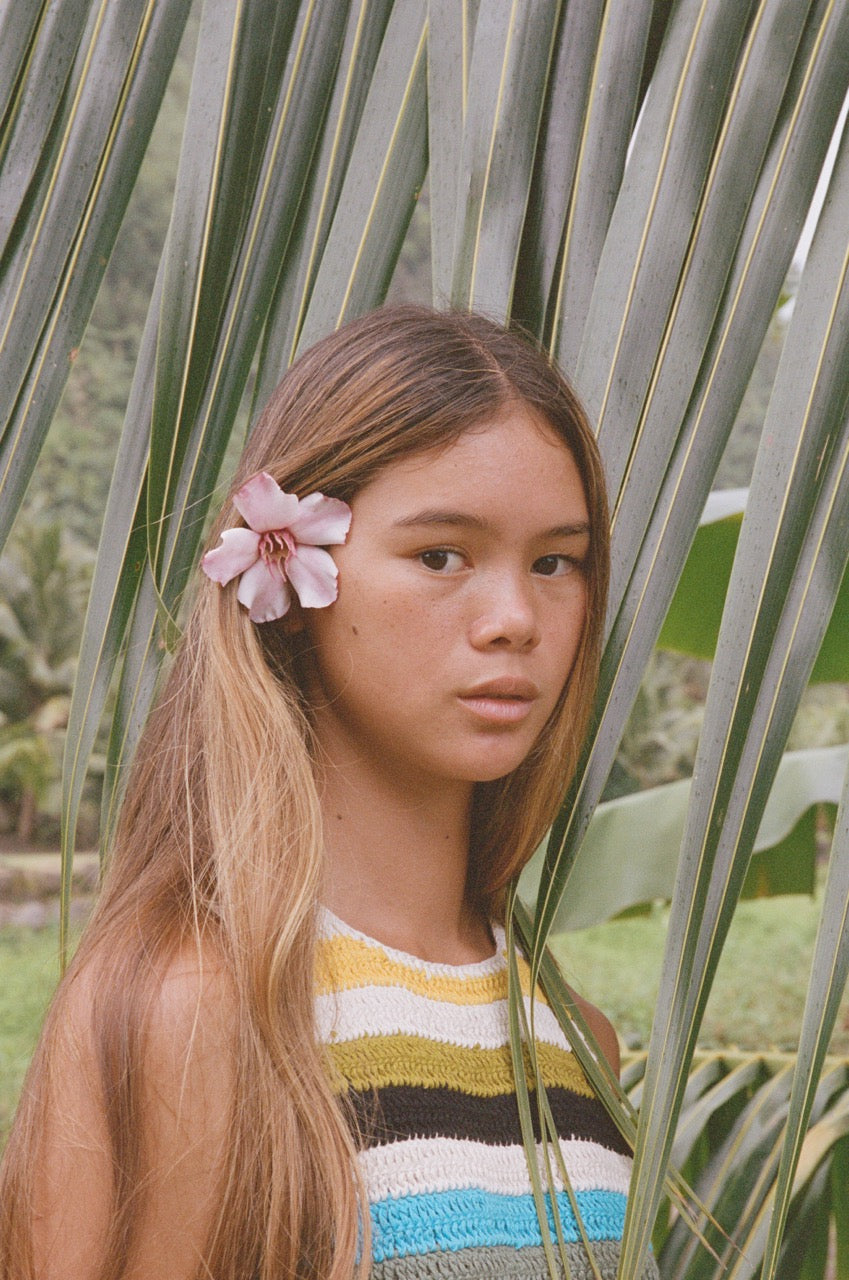 Analog portrait of model with flower in her hair among palm leaves in Tahiti, French Polynesia, shot on film in soft natural light