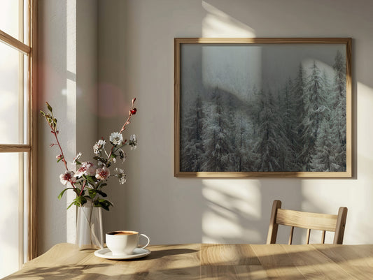 Analog winter forest landscape print of snow covered alpine trees in mist, shot on 120mm film in the Swiss Alps, displayed in a wooden frame in a sunlit minimalist interior