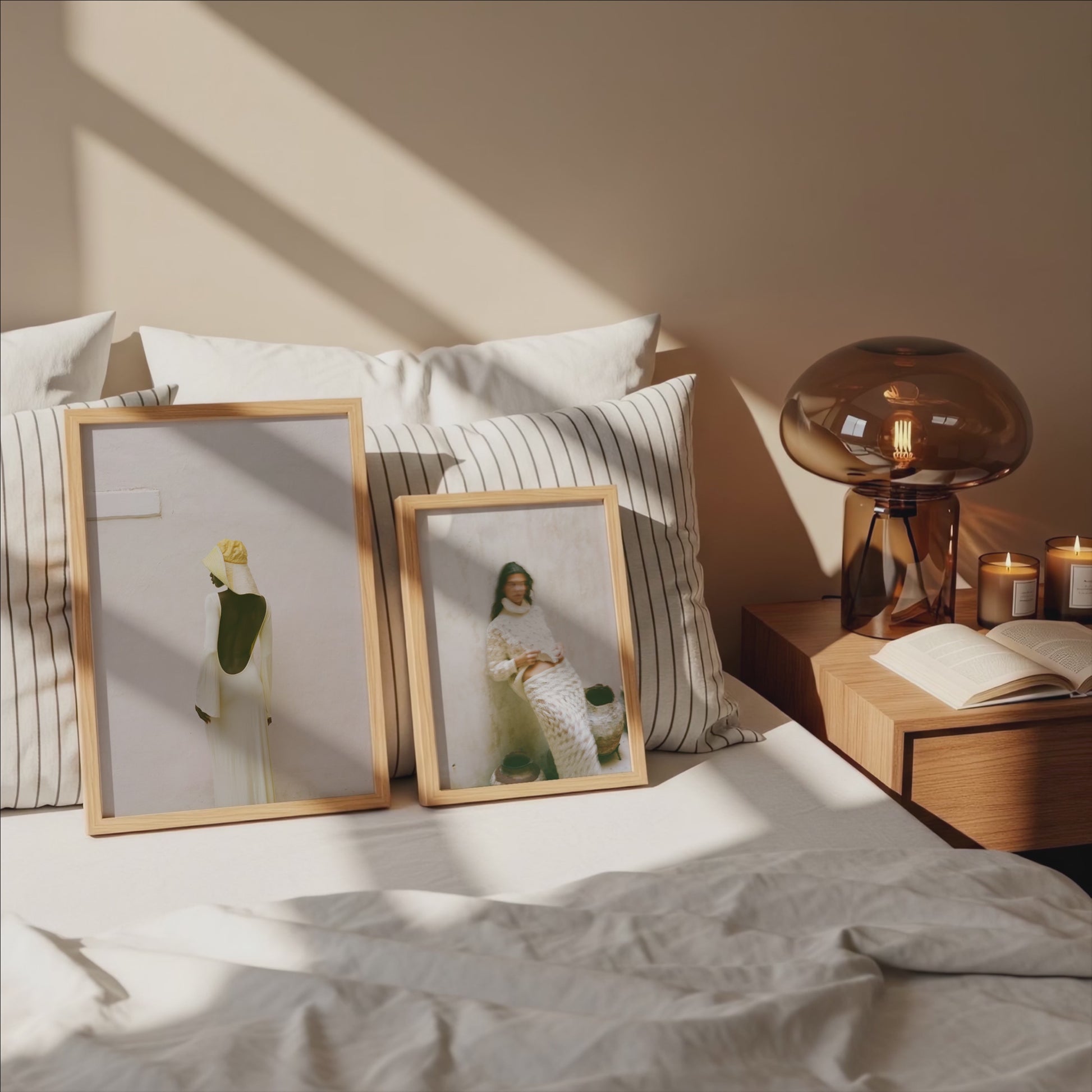 Analog fine art photography prints of women in neutral tones displayed in wooden frames on a sunlit bed, shot on 35mm film in a minimalist interior bedroom setting