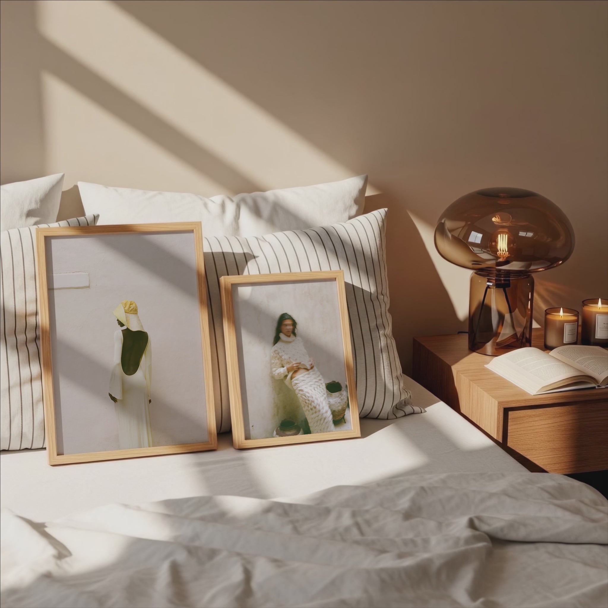 Analog fine art photography prints of women in neutral tones displayed in wooden frames on a sunlit bed, shot on 35mm film in a minimalist interior bedroom setting